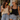 Two women standing outdoors at a cafe, smiling and laughing while holding iced drinks. The woman on the left wears a cream lace camisole and light-wash wide-leg jeans, and the woman on the right wears a black camisole and light-wash denim shorts.