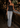 A woman posing in a modern bar setting, wearing a black satin strapless top and light-wash blue flare jeans, holding a small black handbag.